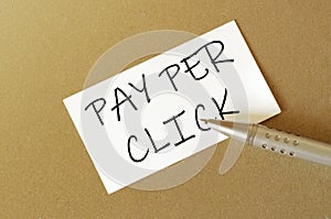 Pen, white paper with text PPC Pay per click on the brown background