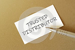 Pen, white paper with text Trusted Distributor on the brown background