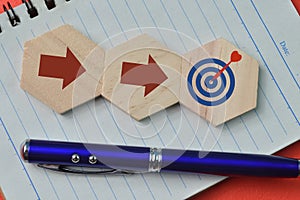 Pen and wooden hexagon with arrows and target symbols. Business strategy and action plan concept