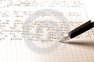 Pen writes the text on a squared paper photo