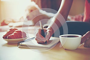 Pen writing on notebook with coffee