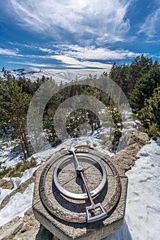 Penalara Natural Park winter scene. Old compass at `Mirador de la Gitana` viewpoint covered with snow. Madrid Community, Spain