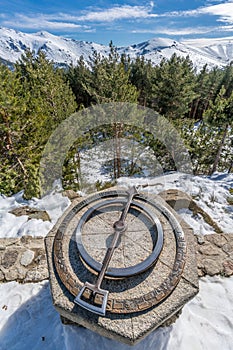 Penalara Natural Park winter scene. Old compass at `Mirador de la Gitana` viewpoint covered with snow.