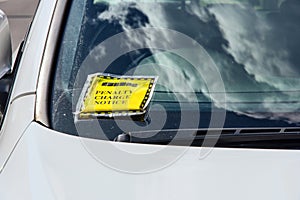 Penalty charge notice (parking fine) attached to windscreen of white car parked in high street London England