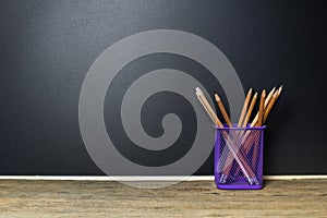 Pencil in basket on wood table with Blackboard Chalk Board