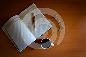 Pencil, blank journal, reading glasses and cup of coffee