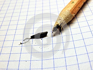A pencil with a broken lead on a checkered sheet of paper