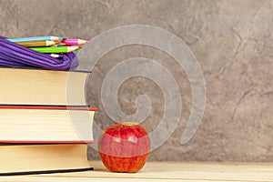 Pencil case on a pile of books with an apple
