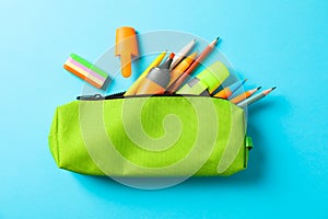 Pencil case with school supplies on blue background