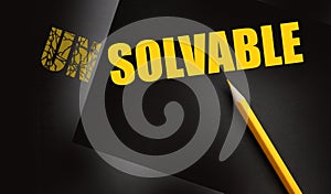 Pencil changing the word Unsolvable into Solvable yellow on black. Business and career solutions concept