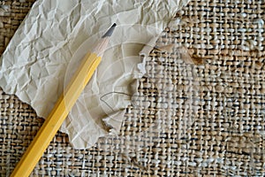 pencil with a chewed end next to crumpled blank paper on a textured rug