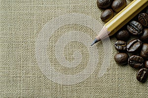 A Pencil and Coffee Beans on a Textured Fabric Surface