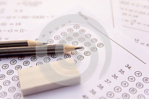 Pencil and eraser on answer sheets or Standardized test form with answers bubbled. multiple choice answer sheet