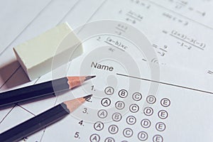 Pencil and eraser on answer sheets or Standardized test form with answers bubbled. multiple choice answer sheet