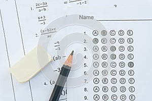 Pencil and eraser on answer sheets or Standardized test form with answers bubbled. multiple choice answer sheet