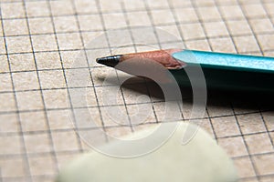 Pencil and eraser on brown graph paper of notebook or page of retro sketchbook