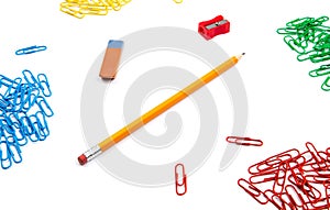 Pencil, eraser, sharpener, paper clips lie in different angles of the sheet on a white background. Hero image and copy space