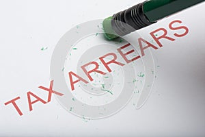 Pencil Erasing the Word `Tax Arrears` on Paper