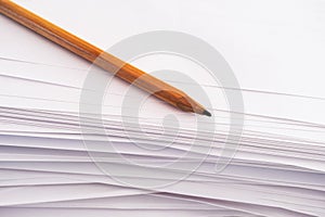 A pencil lies on a stack of paper sheets