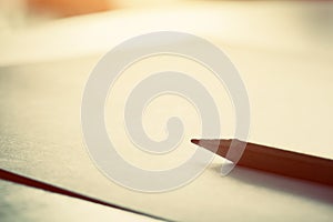 Pencil lying on blank paper in morning light.