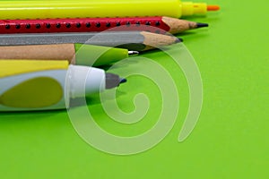 Pencil, marker, ball pen close up macro shot on vibrant green background