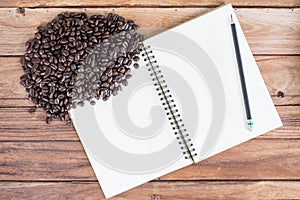 Pencil, notebook, coffee bean on wooden background