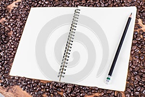 Pencil, notebook, coffee bean on wooden background