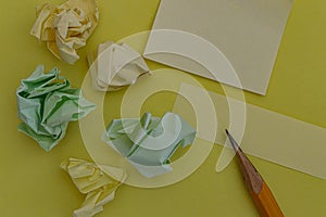 Pencil notes stickers and crumpled paper on a yellow backgroun copy space