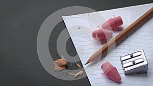 Pencil and Pencil Sharpener and Pink Erasers on Notepad Paper