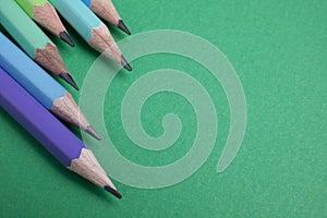 Pencil placed on green paper background with copy space