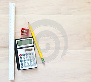 1 pencil, a pencil sharpener, a calculator and a triangular ruler on a wooden desk