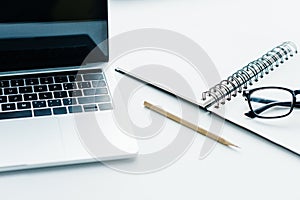 Pencil, textbook with eyeglasses and laptop on white surface