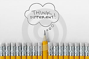 Pencil tip standing out from croud of pencil rubber erasers with Think different word on thought bubble photo
