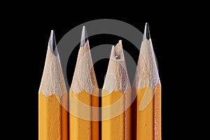 Pencil tips on black background, one broken