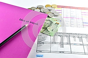 Pencill, money, pink notebook and calculator placed on document