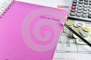 Pencill, money, pink notebook and calculator placed on document