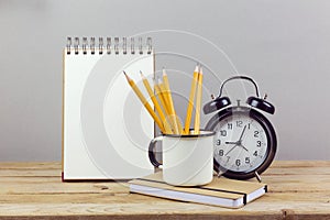 Pencils, alarm clock and notebook on wooden table. Business planning process