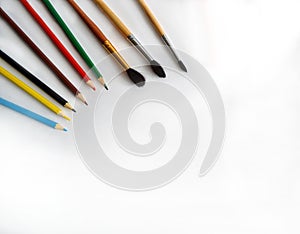 Pencils and brushes lie on a white background on the table