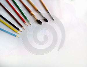 Pencils and brushes lie on a white background on the table