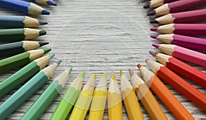 Pencils circle which lies on a wooden background