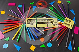Pencils in circles, titles Back to school and drawing of school bus drawn on the pieces of paper on the chalkboard