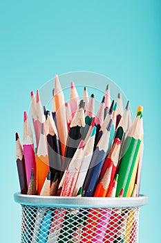 Pencils of different colors in a glass on a blue background