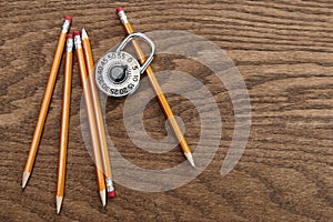 Pencils and lock on wood surface