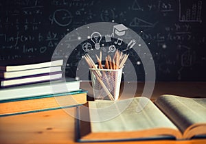 Pencils and Open books with formulas on the chalkboard .education concept