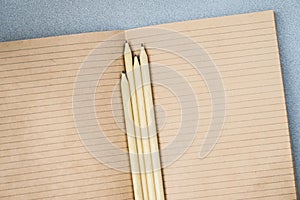 Pencils and open notebook paper from craft paper, top view, texture. Place for text, the concept of starting school