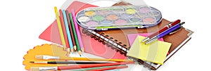 Pencils, paints, notebooks and other stationery isolated on a white background. Wide photo.