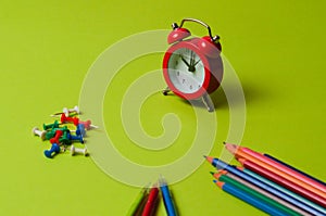 Pencils, pens, push pins and clock on green designer paper