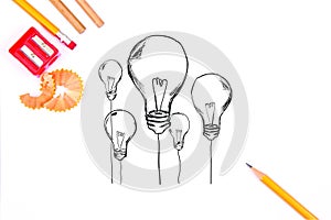 Pencils, a red sharpener and sketched lightbulbs