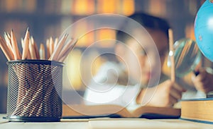 Pencils on a wooden table and asian child industrious is sitting at a desk . background. Educational background photo