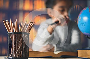 Pencils on a wooden table and asian child industrious is sitting at a desk . background. Educational background photo